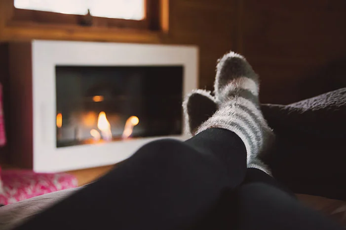 Füße mit Wollsocken vor Kamin